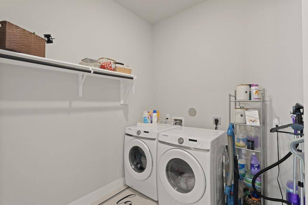 Spacious laundry room with full-size washer and dryer hookups, overhead shelving for storage, and convenient wall space for organization.