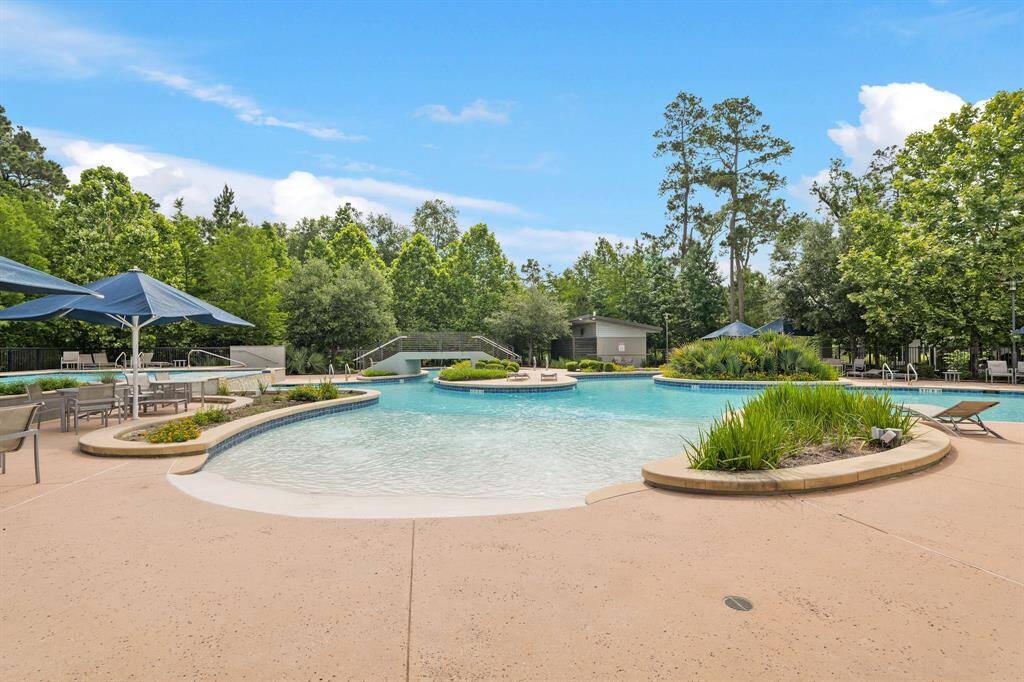 Resort-style community pool with sun shelves, shaded seating, and a peaceful backdrop of lush greenery—perfect for summer relaxation.