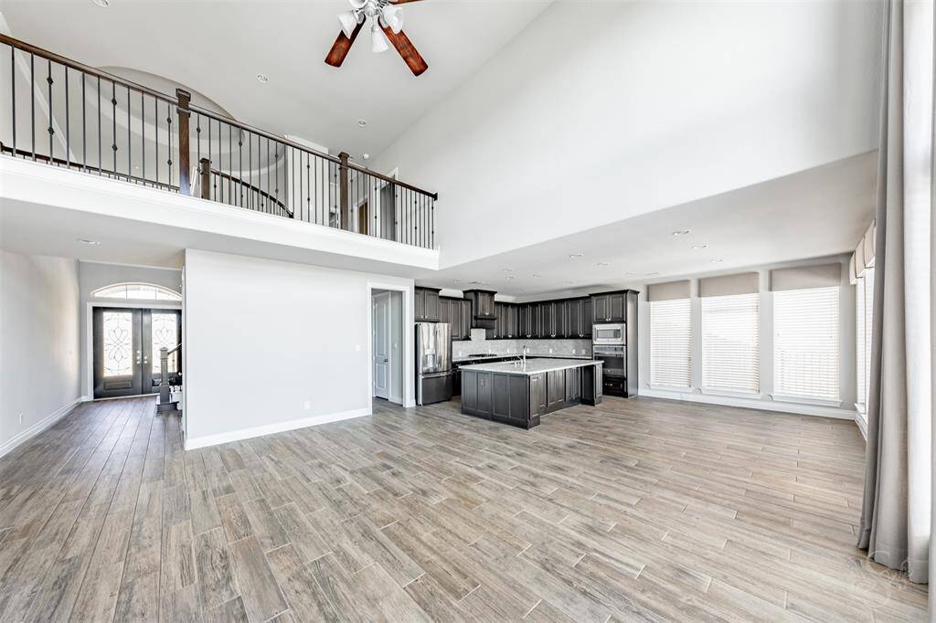 Open-concept living blends seamlessly from the chef's kitchen into the light-filled family room, all anchored by gorgeous wood-look tile floors. A wall of windows and soaring ceilings create a stunning backdrop for everyday living or special occasions.