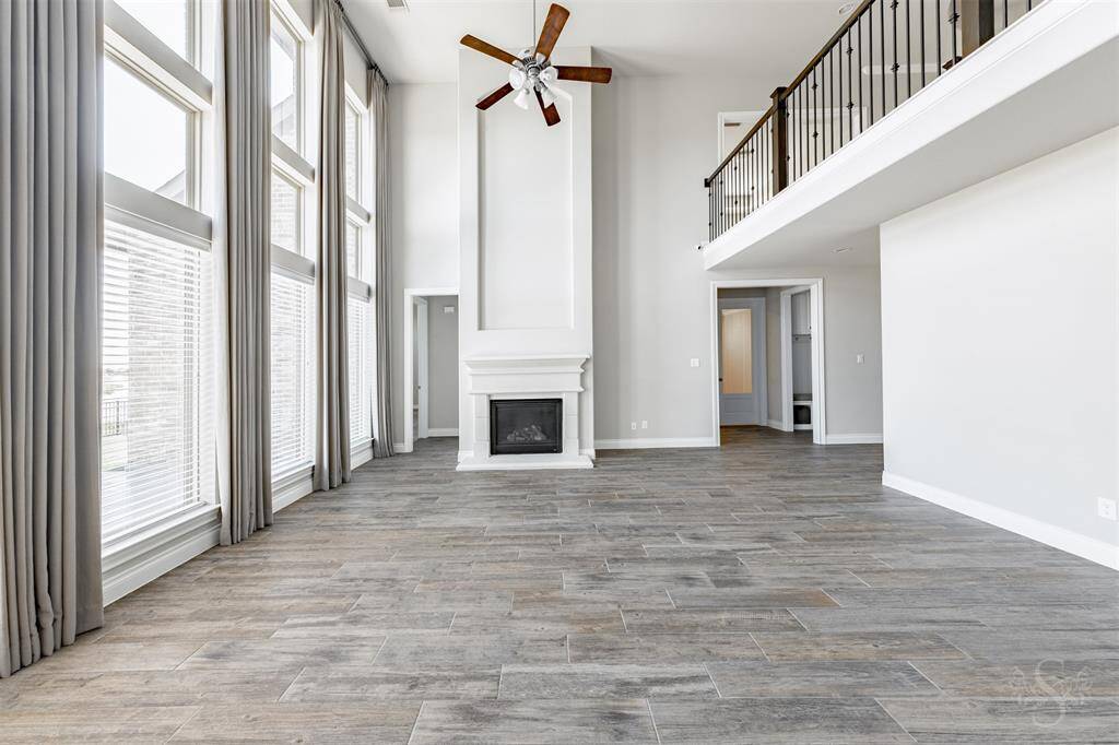 The floor-to-ceiling windows and a modern fireplace create a dramatic focal point in this inviting family room. Overlooking the second-floor balcony, this space feels grand yet welcoming.