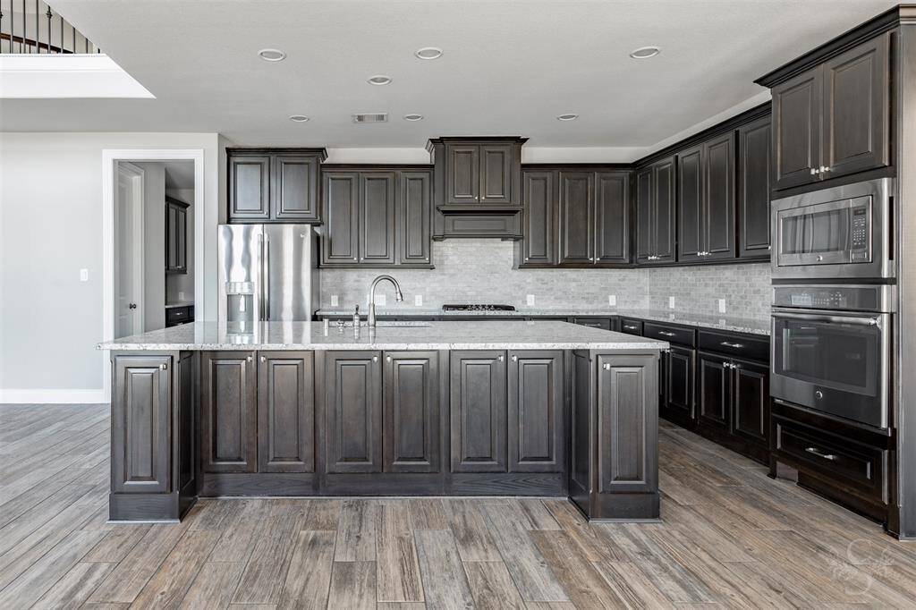 The designer kitchen impresses with gorgeous cabinetry, stainless steel appliances, and a sprawling granite island with bar seating- ideal for both everyday living and elegant entertaining. Sophisticated finishes and open flow make this space as functional as it is stunning.