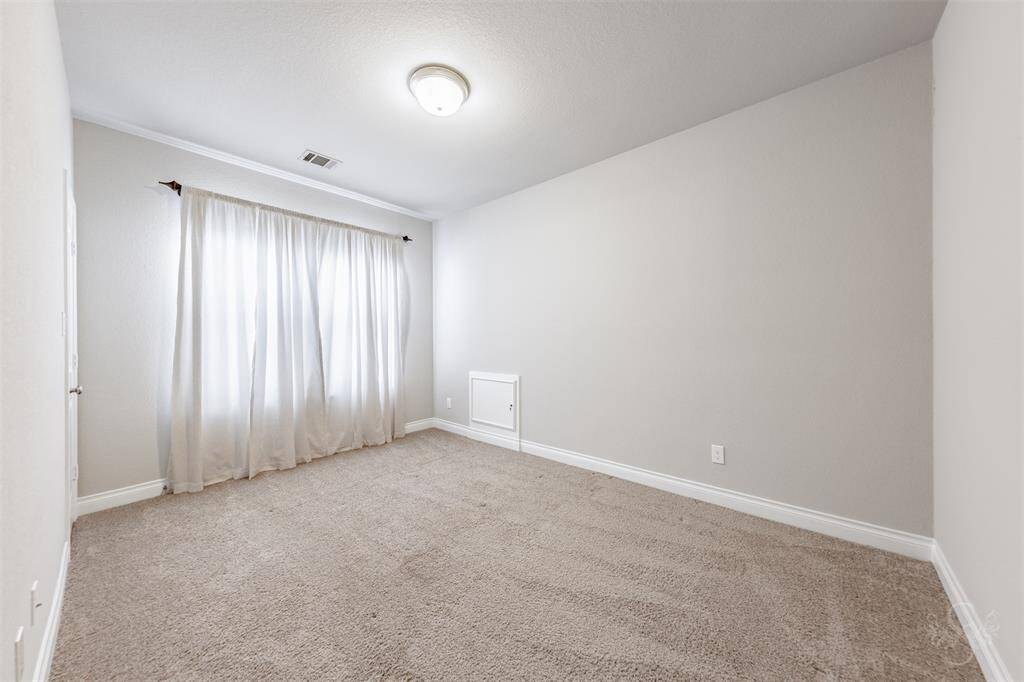 This spacious upstairs bedroom features plush carpeting and soft natural light, creating a peaceful setting for rest or study. Neutral tones and ample wall space provide flexibility for any design style including a good sized bed, furniture and desk.