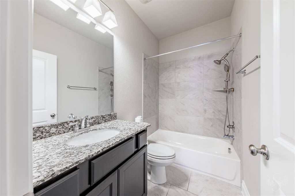 Elegantly appointed with polished granite counters, rich cabinetry, and sleek tile surround in the tub/shower combo, this full bath offers style and functionality for guests or family.
