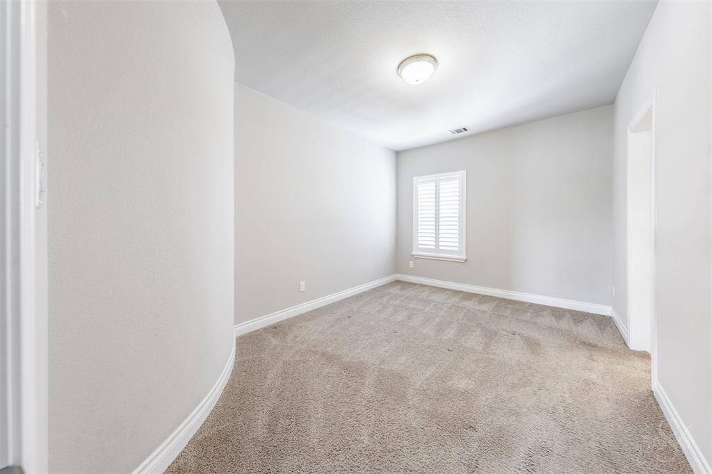 This bright and inviting bedroom enjoys a plantation shutter window and a unique curved entry nook, offering architectural interest and cozy appeal.