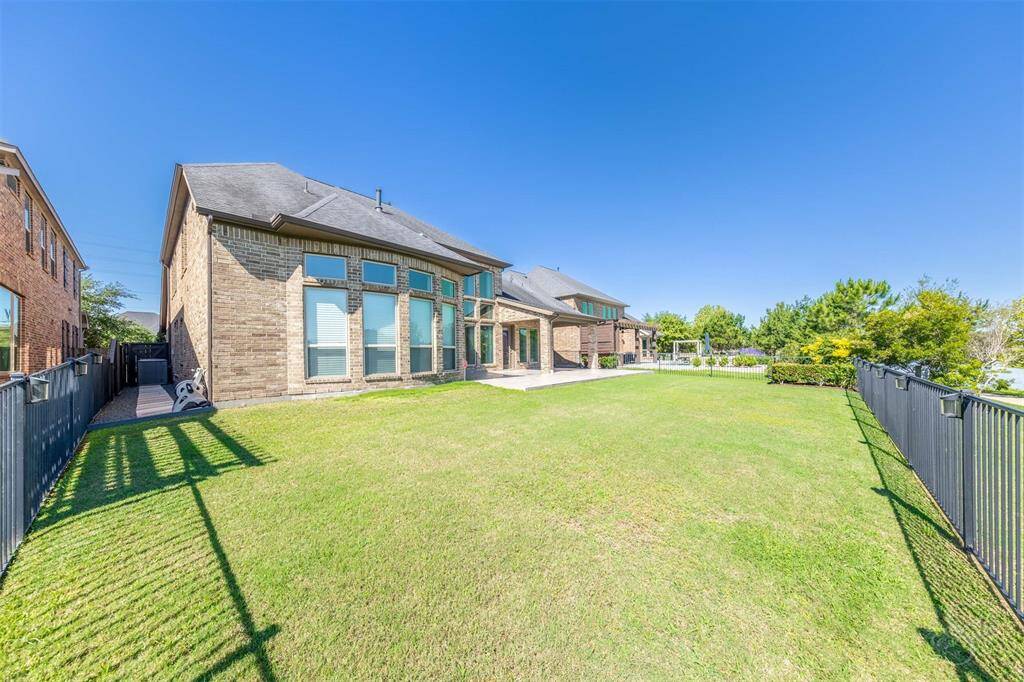 With a striking two-story window wall and extended tile patio, this rear elevation commands attention. The home’s clean architectural lines blend beautifully with the surrounding waterfront landscape.