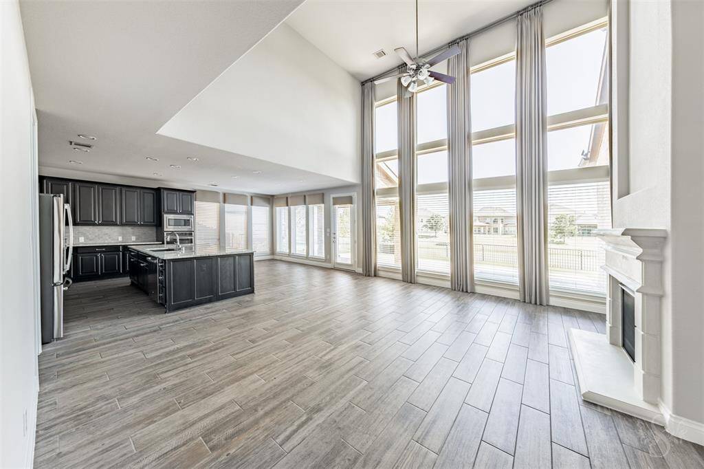 Soaring two-story ceilings and a dramatic wall of windows flood the open-concept family room with natural light. The generous layout easily accommodates all the furniture you need to host both family and guests. A gourmet kitchen with dark cabinetry, granite countertops, and an expansive island completes the perfect space for entertaining.