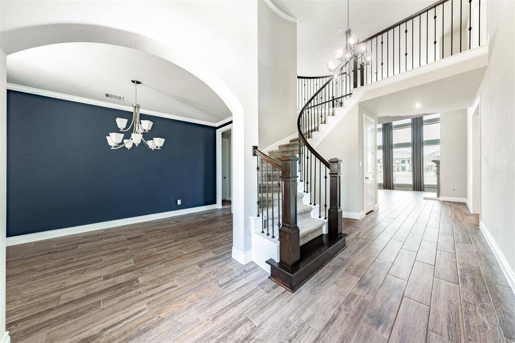 The grand entry welcomes you with a sweeping curved staircase with elegant wrought iron spindles. A formal dining room with rich custom accent walls and crown molding sets the tone for sophisticated gatherings.