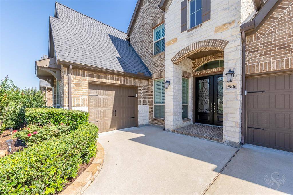 Welcome guests through a stately stone-accented entrance framed by lush landscaping and elegant double doors with wrought iron detailing. The single-car bay of the 3-car garage offers flexible use—perfect for a workshop, home gym, or storing recreational gear.