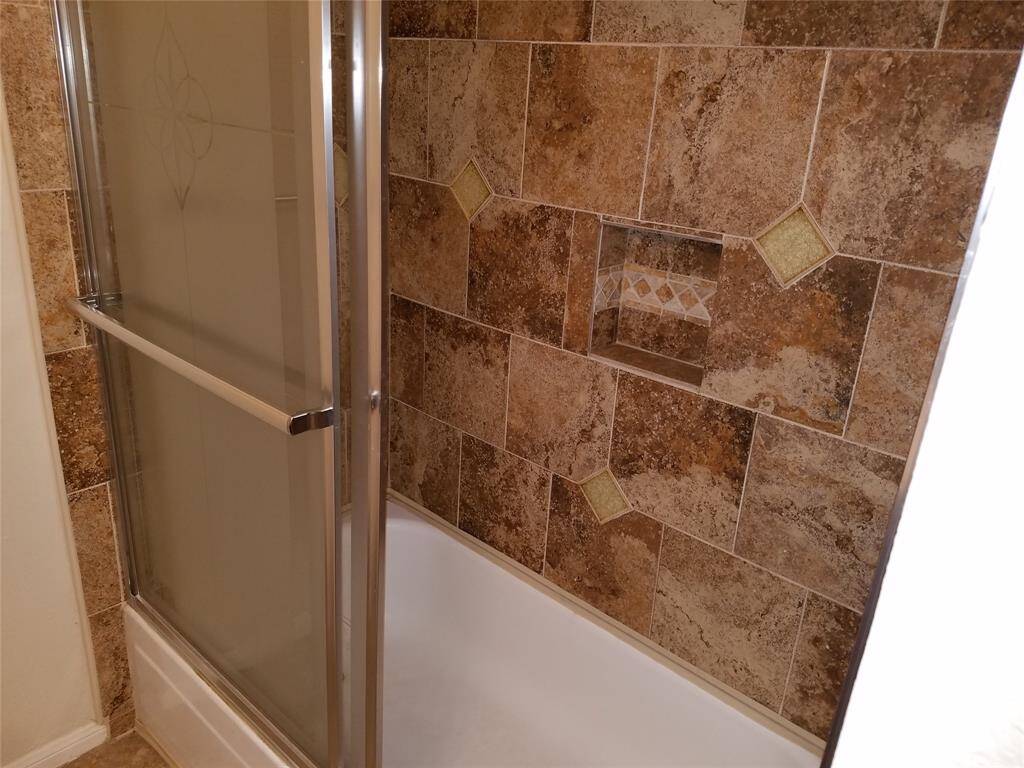 Bath and shower in the second bedroom, complete with custom tile surround and built ins.