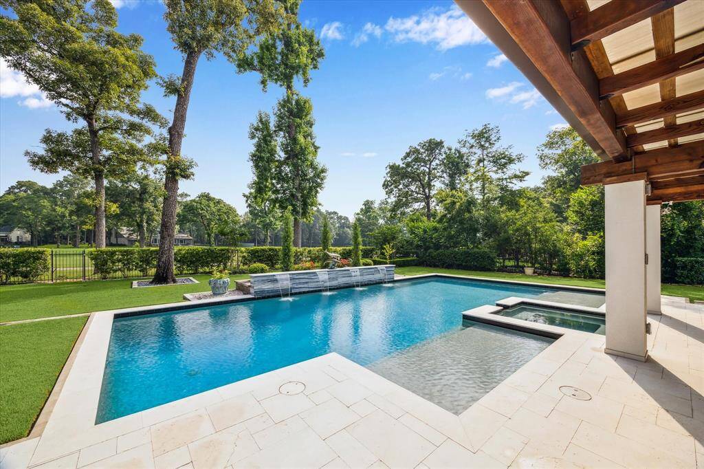 Step into the resort-style backyard featuring a modern rectangular pool with an integrated sun deck and spa, surrounded by travertine decking.. An extensive covered patio provides the perfect setting for outdoor dining, lounging, or entertaining—rain or shine.