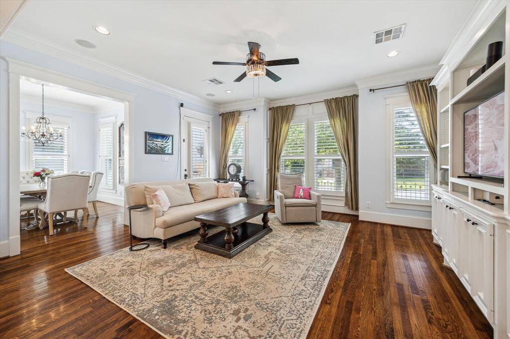 The living room also boasts built-ins, surround sound, hardwood floors, plantation shutters, recessed lighting, and a stylish ceiling fan.