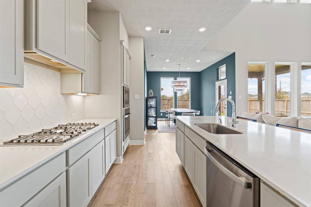 Sleek and open kitchen layout with quartz countertops, designer backsplash, and a seamless flow into the dining and living areas filled with natural light.
