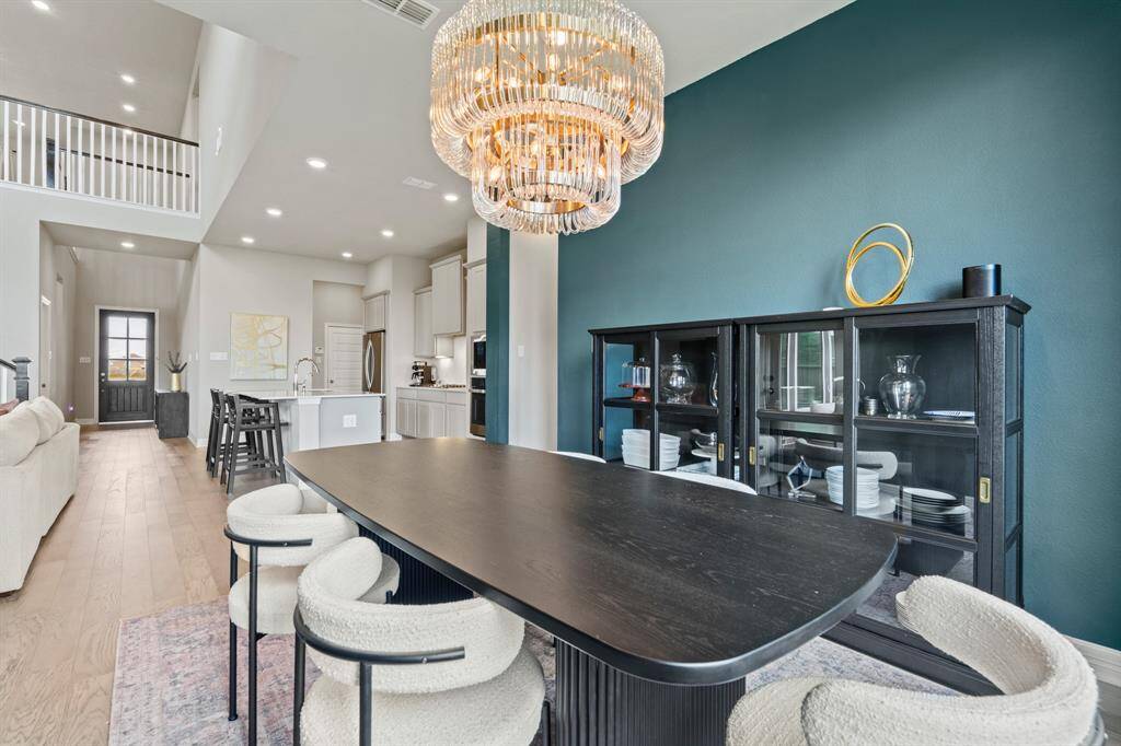 Elegant dining area highlighted by a dramatic chandelier, bold accent wall, and open layout that flows beautifully into the kitchen and living spaces.