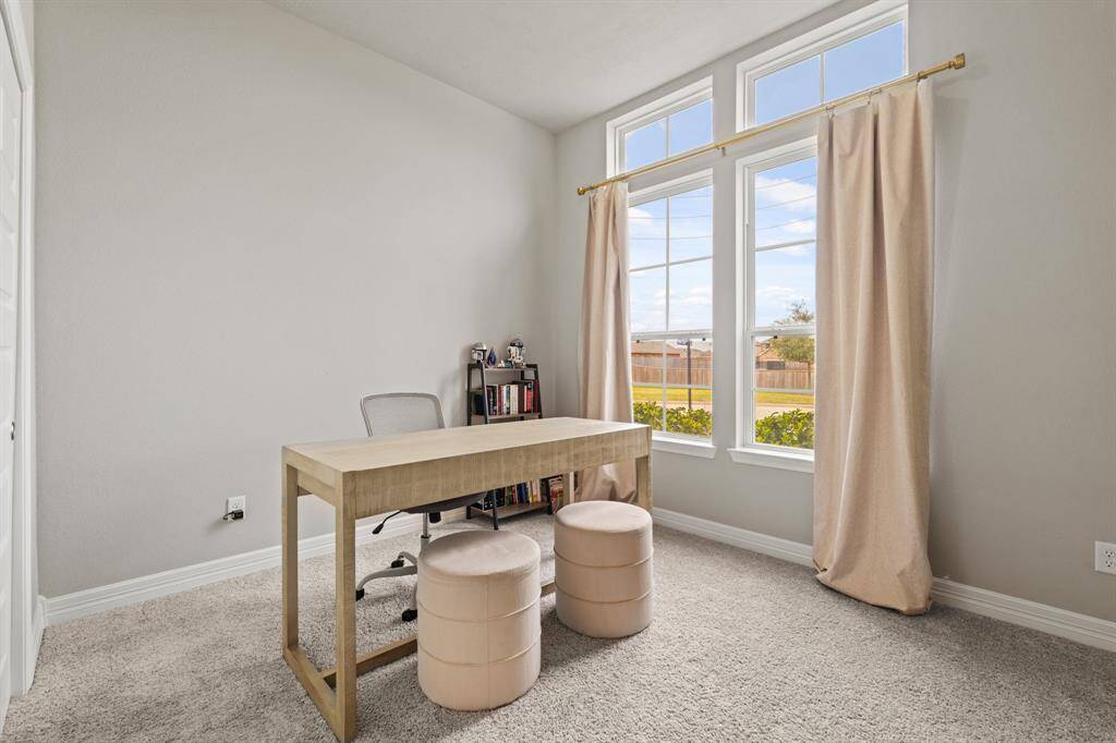 Bright and serene home office with oversized windows, plush carpet, and a simple layout perfect for productivity.