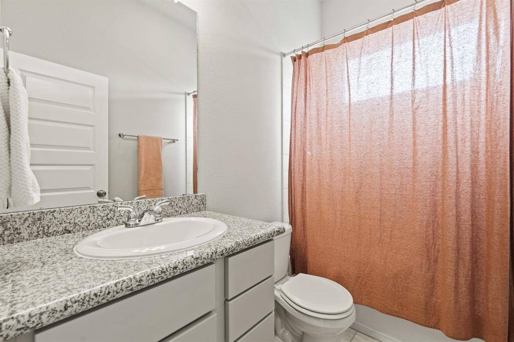 Well-appointed guest bath featuring granite countertops, modern fixtures, and a warm color palette.