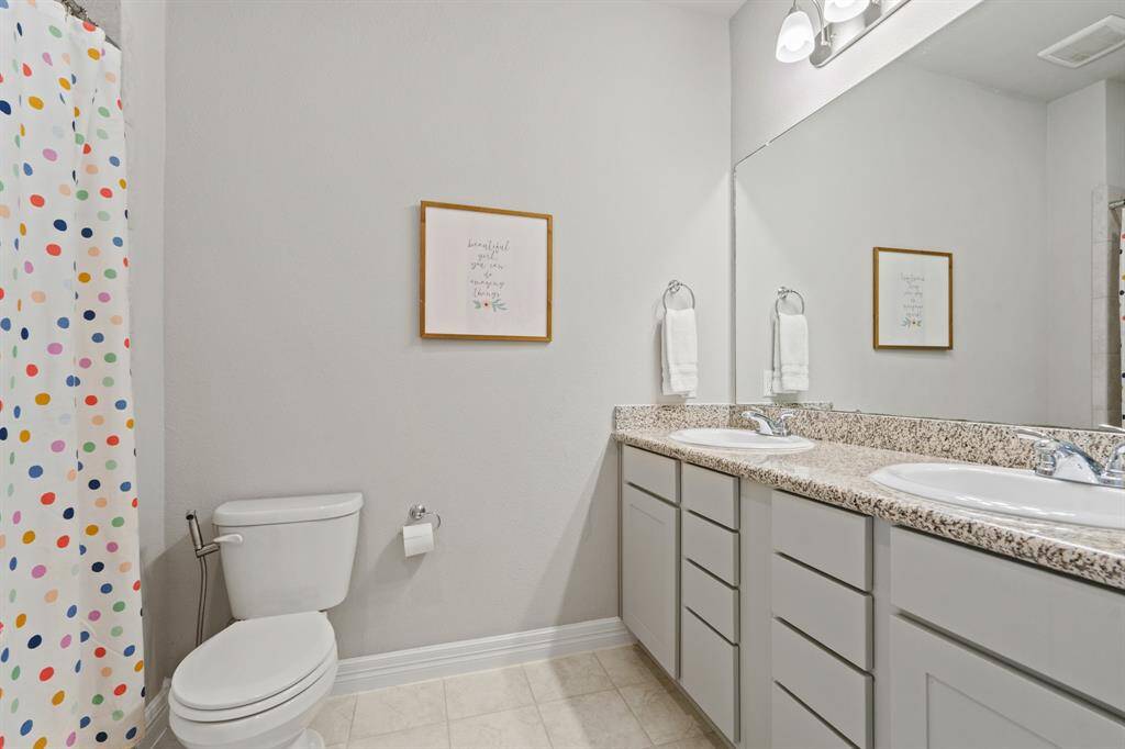 Fresh and modern bathroom with granite countertops, dual sinks, and playful touches perfect for guests or family.