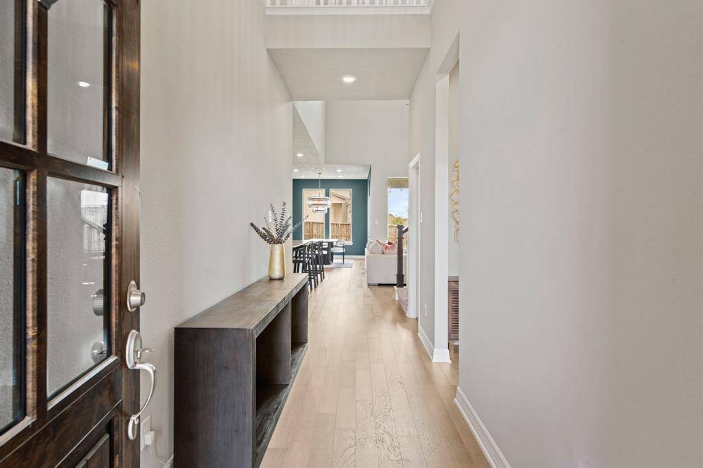 Step into a bright and inviting entry hallway with soaring ceilings, elegant wood flooring, and a stylish view into the heart of the home.