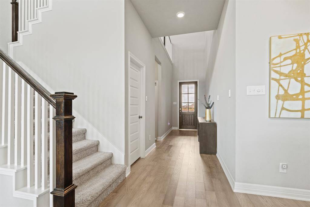 Elegant foyer with high ceilings, rich wood flooring, and a view of the beautiful stairway that adds warmth and character right from the entrance.