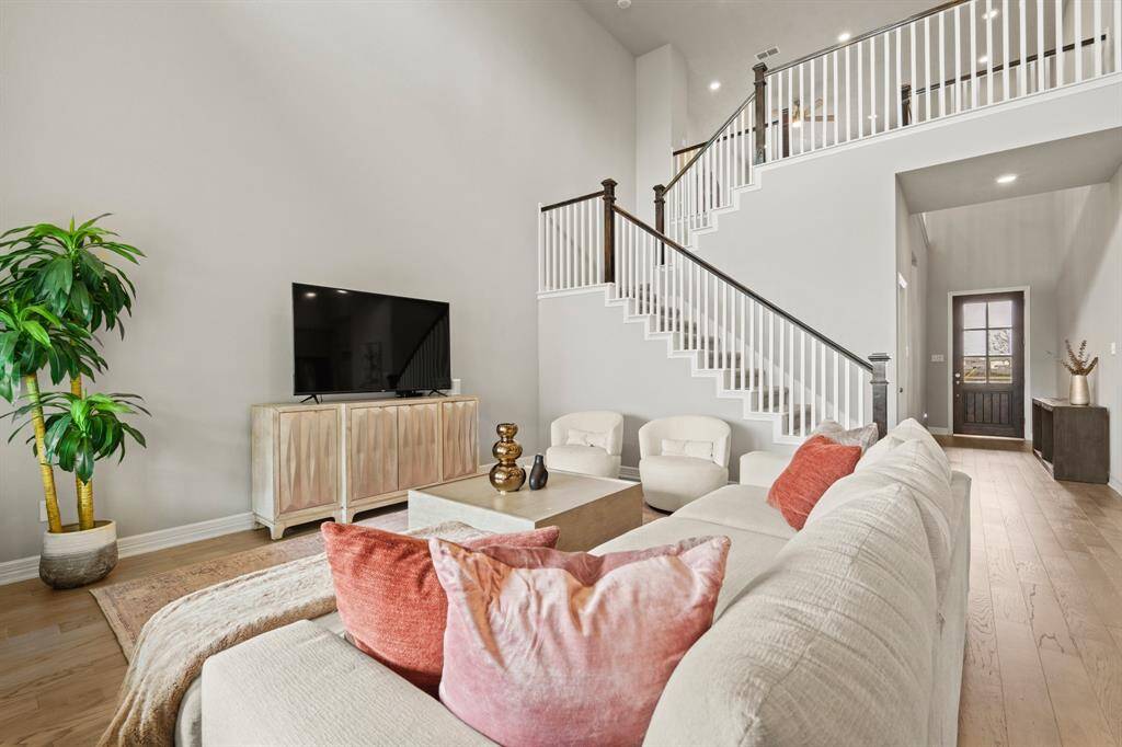 Spacious living room with vaulted ceilings, modern railing accents, and a cozy yet stylish setup perfect for relaxing or entertaining.