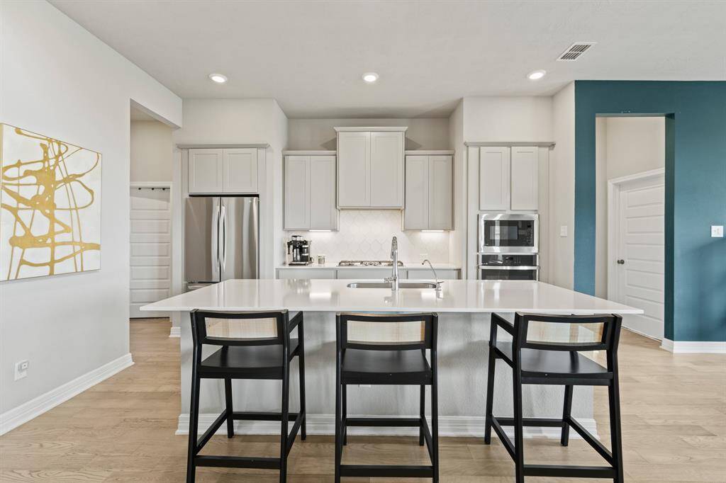 Bright and stylish kitchen with a large center island, crisp white cabinetry, and modern stainless steel appliances offering both functionality and flair.