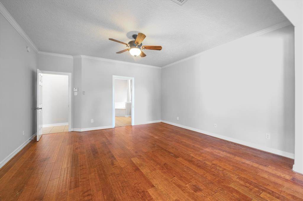 Elegant first-floor primary bedroom with wood floors and a ceiling fan.