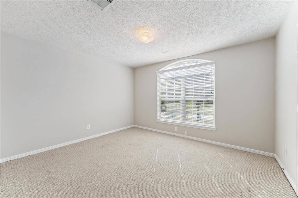 Bright and airy secondary bedroom, a large window allowing for ample natural light, and a view out the outdoors.