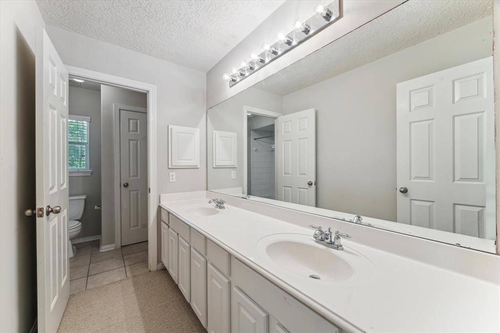 Third full bathroom featuring double sinks with ample counter space and provides a separate area for the toilet.