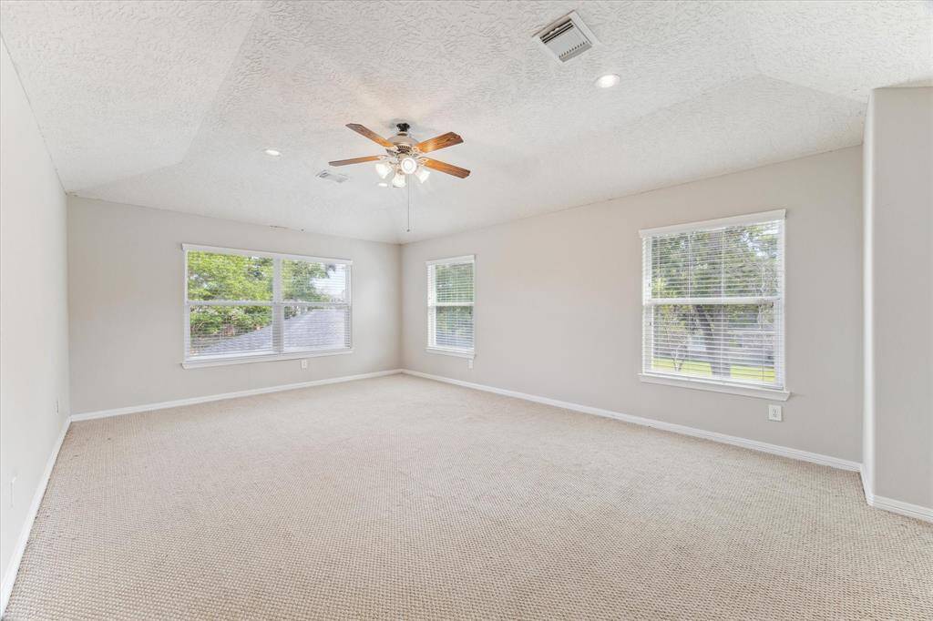 This game room has vaulted ceilings, fresh paint, and overlooks the back and side yards.