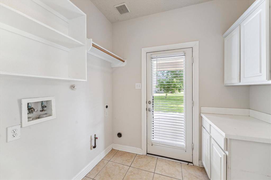 The laundry room in this home features electric or gas connections and built in cabinetry for more storage.