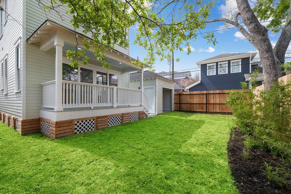 The lovely back yard/garden is ready for you to make it your own space!  covered back porch looks onto back yard/garden.  Glass doors lead to downstairs Primary Suite or second family room/den if you use the upstairs suite as your Primary Suite. Notice back door of garage is open.  This allows cars to exit thru the wooden gate (closed in this photo) into the alley.