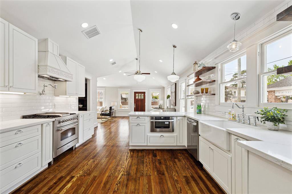 Kitchen boasts high ceilings, hardwood floors, stainless appliances, under cabinet microwave, farmhouse sink, custom lighting and more!