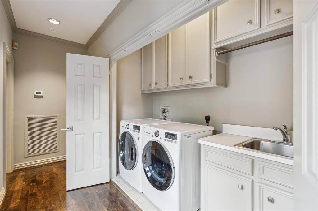 Laundry Room with washer and dryer (included) and storage cabinets. The Laundry Room is bright, cheery, and unapologetically organized. Built-in cabinetry, drip dry hanging space, and folding bar means tasks are a little less “ugh” and a lot more “ahh.” Great upper storage for cleaning supplies and bulk storage.