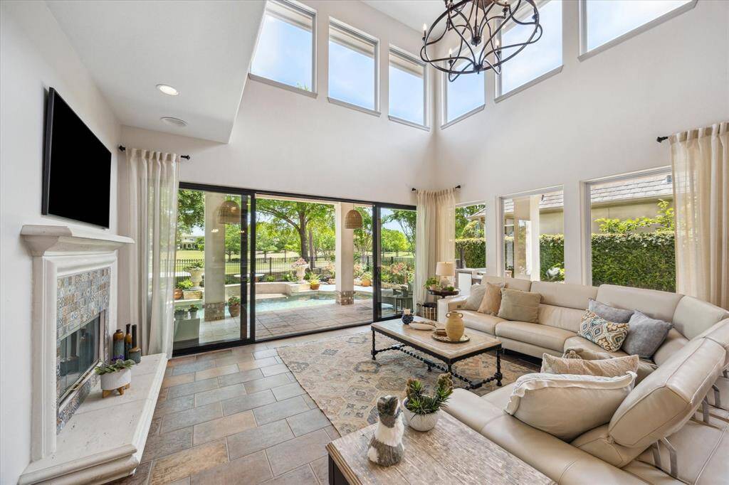 Two story family room with slider doors opening up the room to the pool and golf course. Cast stone fireplace with custom tile brought in from El Salvador. Reclaimed beams, new light fixtures and plenty of natural light!