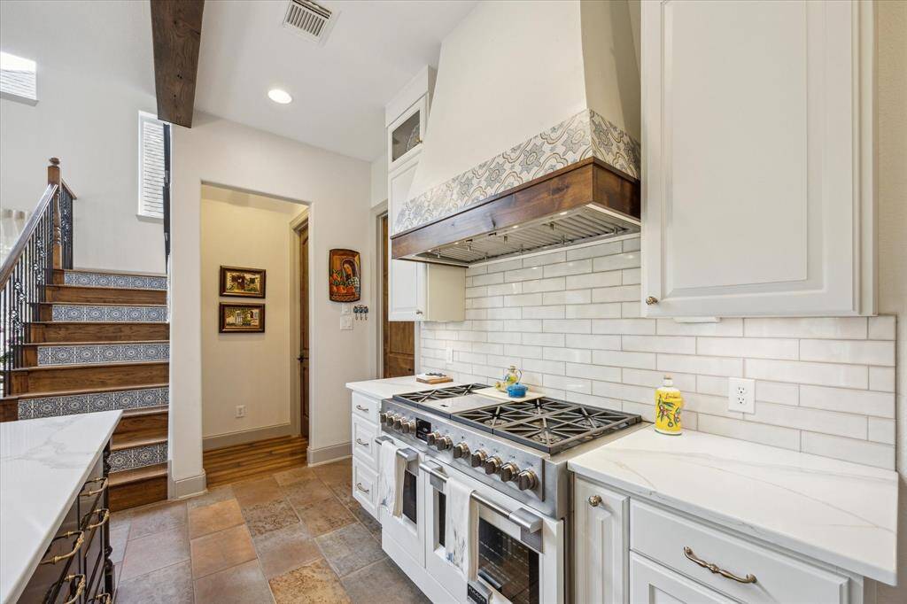 Range, custom vent hood, glazed subway tile backsplash.