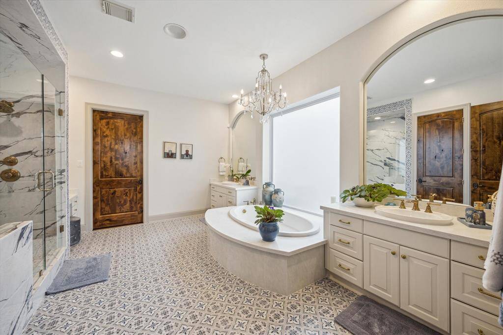 Master bath with new flooring, plumbing, shower, tub, countertops, lighting, mirrors, interior stained doors, and hardware. Separate vanities and additional make up vanity area.