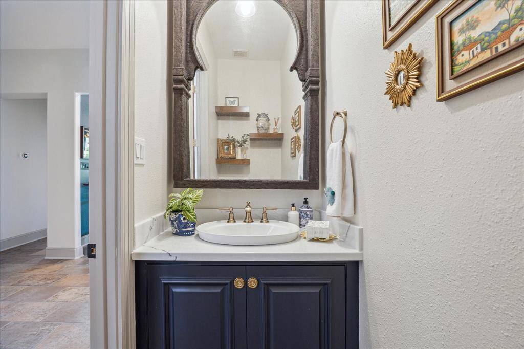 Powder bath down with beautiful Spanish style wood mirror. New cabinetry, plumbing, countertop and lighting. Stained wood floating shelves above the toilet.