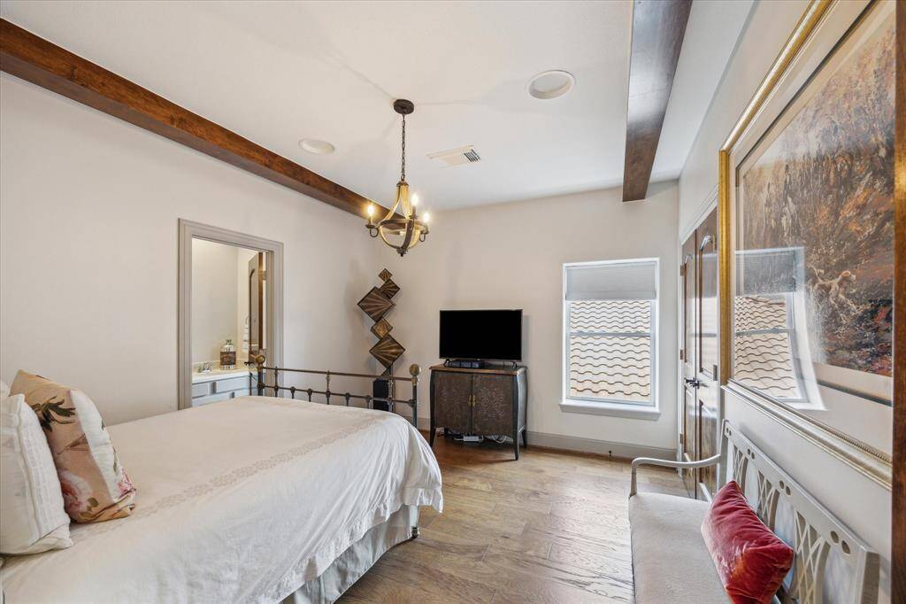Secondary bedroom on the second floor with en suite bathroom. Stained beams and hanging fixture, engineered wood flooring.