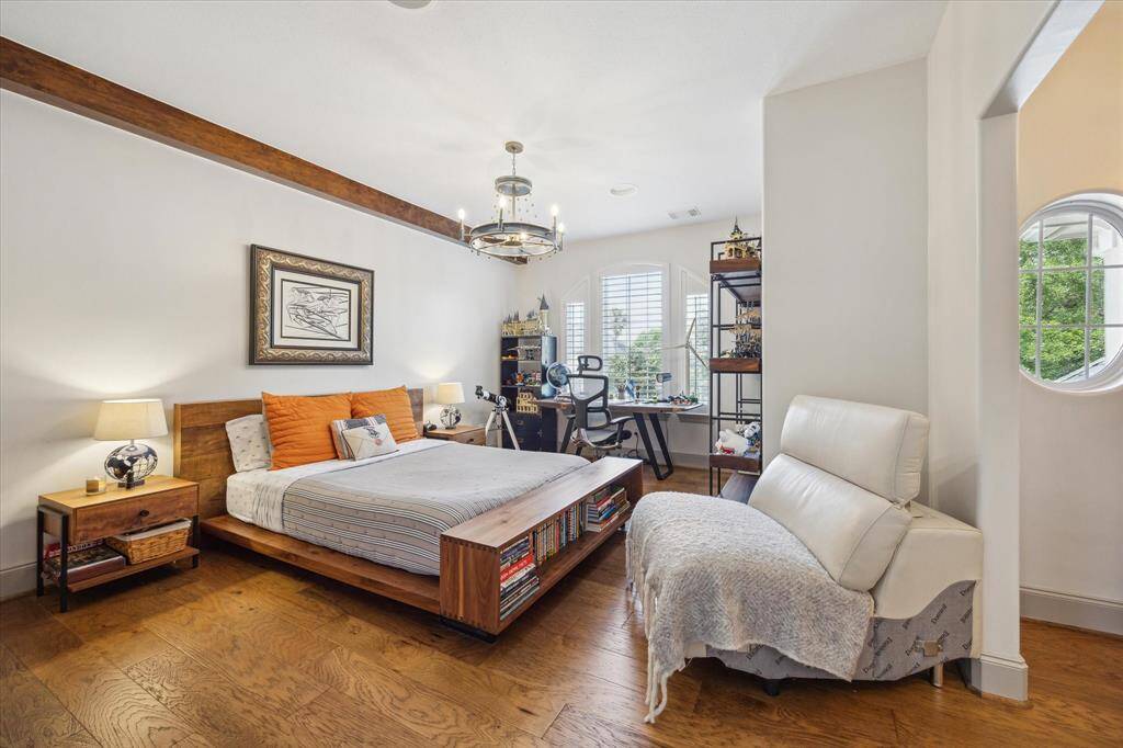 Secondary bedroom on the second floor with stained beam, hanging fixture, engineered wood flooring.
