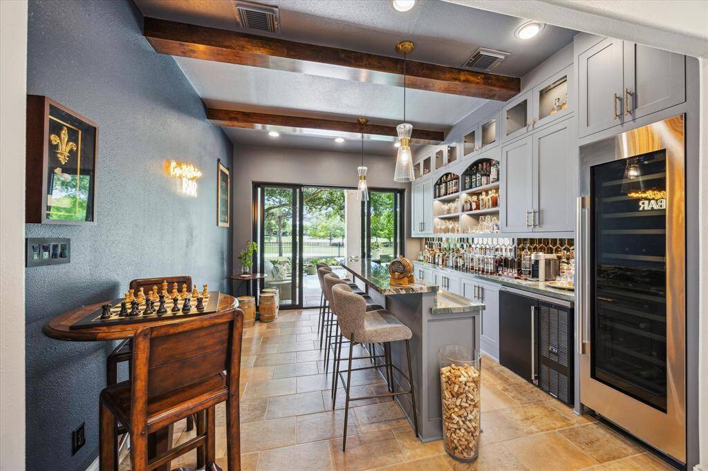 Remodeled study  turned into a cantina bar with sliders opening up the room to the pool and golf course. Stained beams, custom cabinetry, commercial grade appliances, pendant lighting and high bar for entertaining!