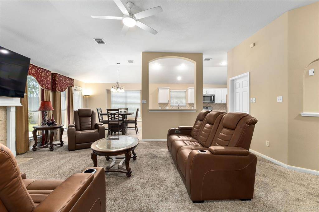 The open layout seamlessly connects to the dining area and kitchen, highlighted by an arched opening. Large windows offer natural light and a ceiling fan for comfort.
