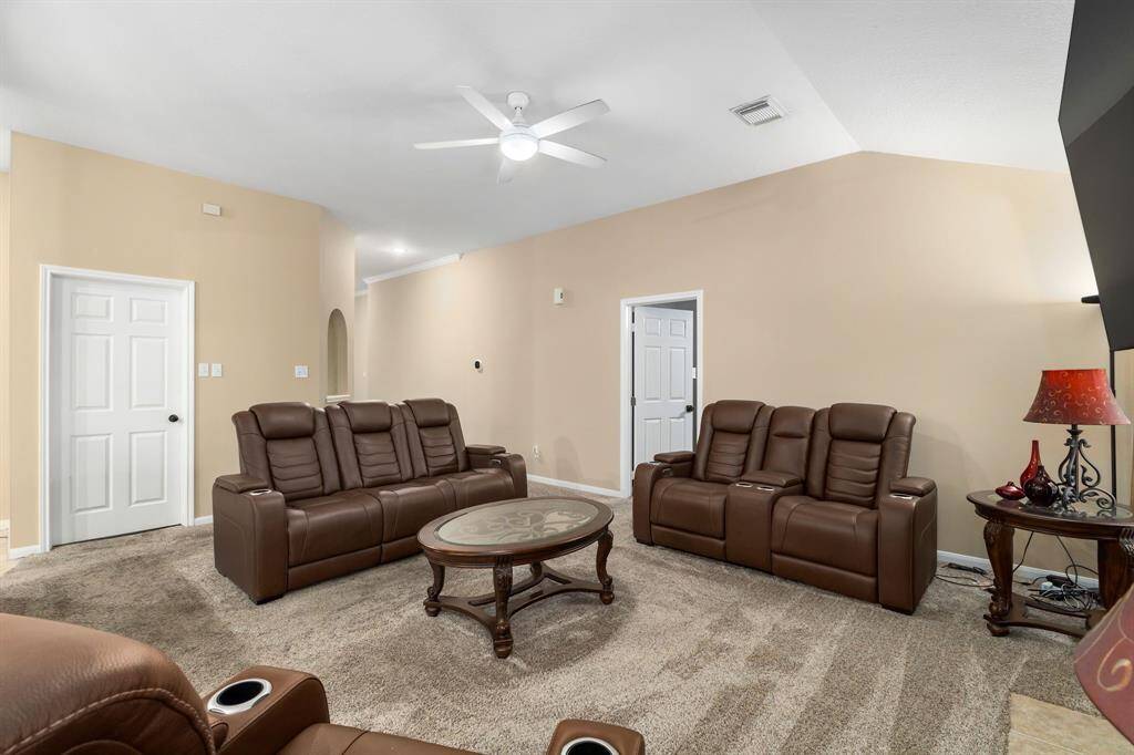Neutral walls and carpet create a cozy atmosphere, complemented by a ceiling fan and ample lighting.