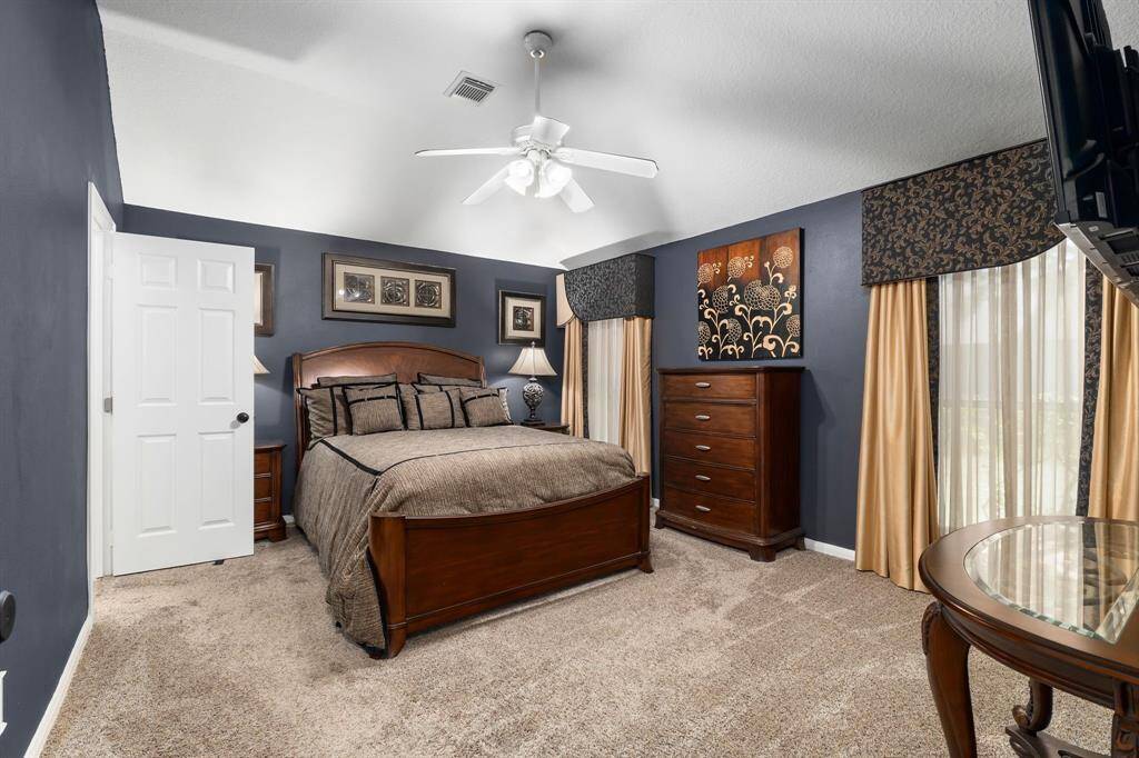 Cozy bedroom with dark blue walls, ceiling fan, and elegant drapery for a warm, inviting feel.