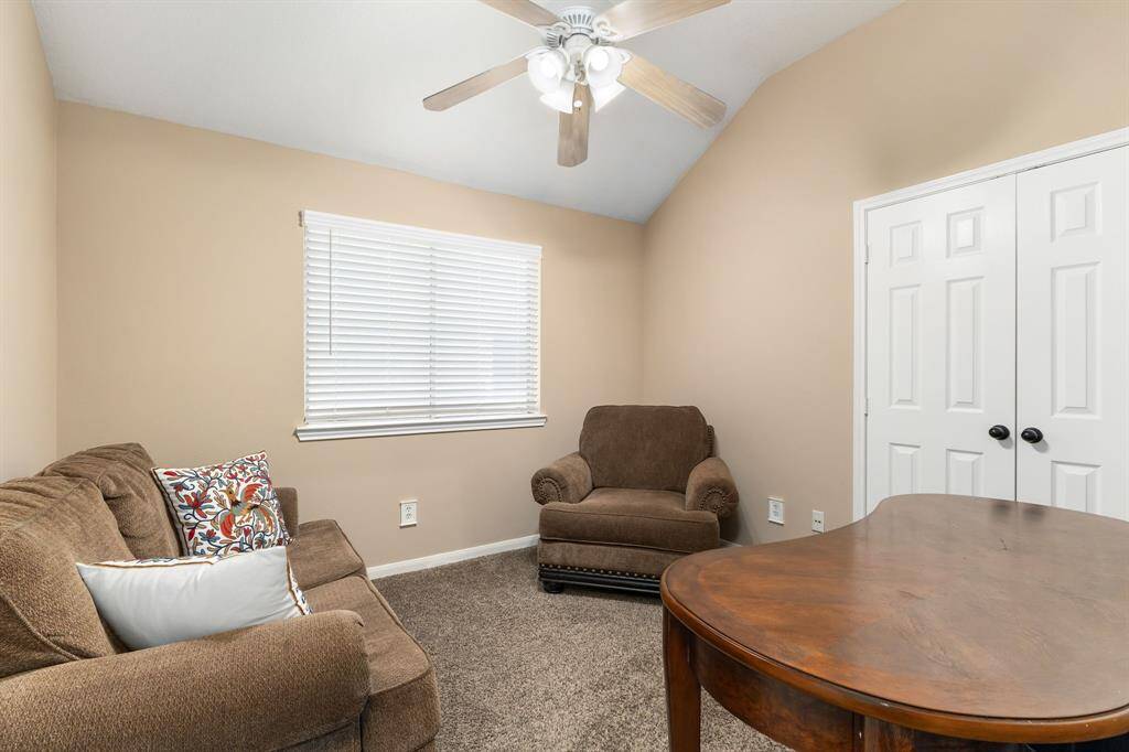 Cozy secondary bedroom with neutral tones, carpet, and ceiling fan—perfect as a home office or reading nook