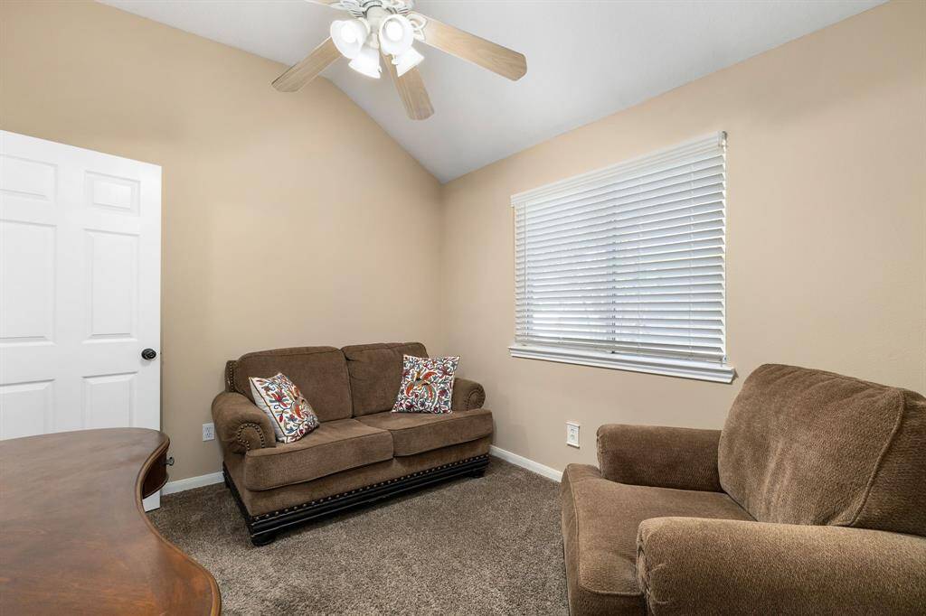 Cozy secondary bedroom room with neutral walls and carpet, featuring a ceiling fan.