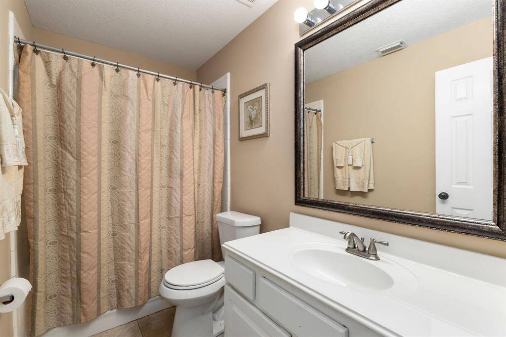 Bathroom with neutral tones, white vanity, large mirror, and a shower-tub combo.