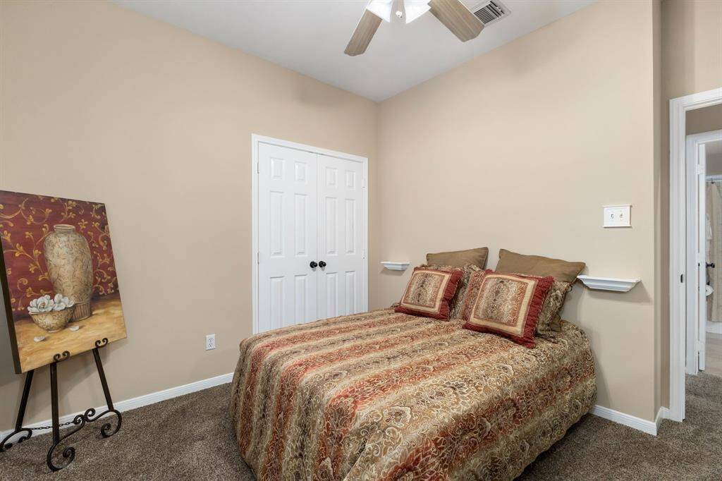 Another view of the guest bedroom, featuring a large arched window, neutral walls, and a ceiling fan for added comfort.