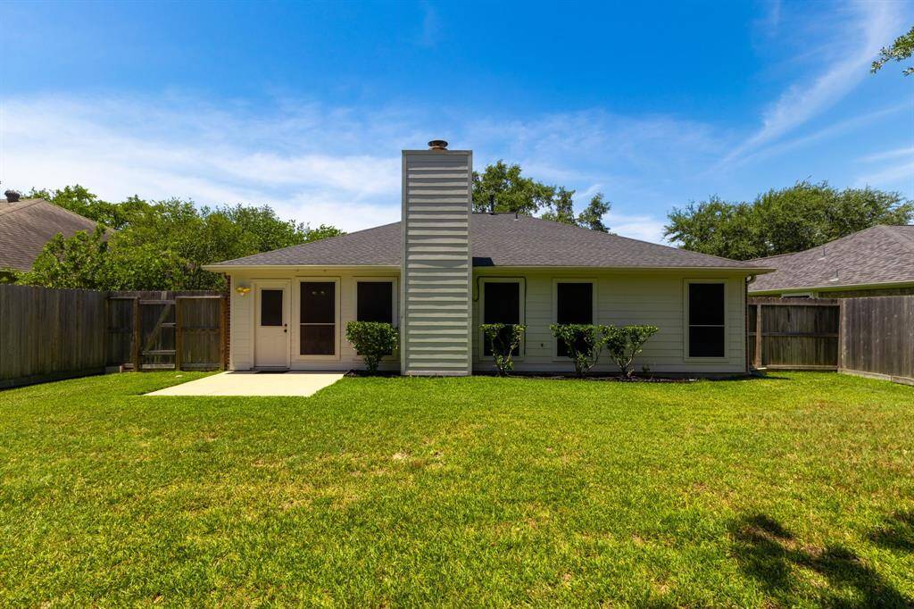 The yard is surrounded by a wooden fence, offering privacy, and includes a small patio area, making it ideal for outdoor activities and relaxation.