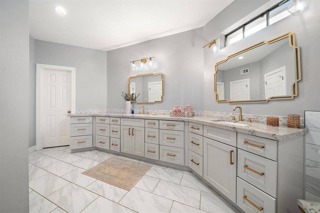 The primary bathroom shines with updated vanities, framed by chic new mirrors and enhanced with elegant, modern lighting.