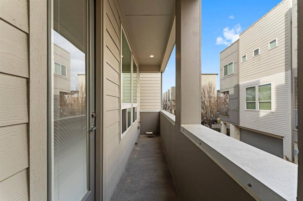Covered balcony with modern beige siding, overlooking residential area.