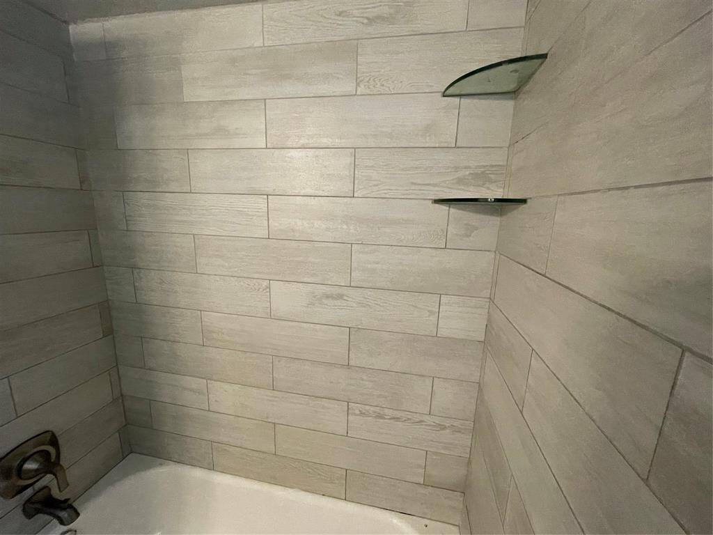 Tub/shower combo all updated with tile and shelving.